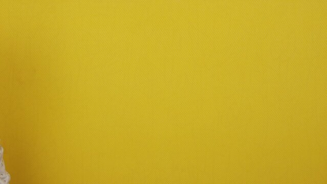 Hands holding a clapper board on a yellow isolated background