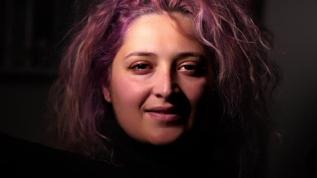 woman with pink hair looking into room at home with dark background. close up