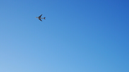 The big four-engine transport airplane is flying far away. Clear blue sky. International air...