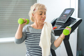 Beautiful mature woman lifting free weights at home