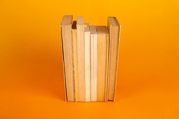 Libros en fila sobre fondo naranja