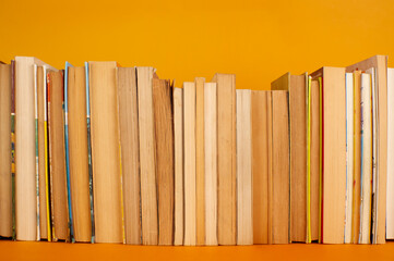 Pila de libros de bolsillo tipo estante sobre fondo naranja