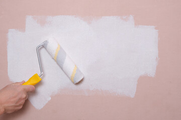 Painting the walls with a paint roller pink with white paint, home repairs.