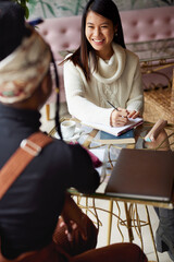 A happy female student sitting in cafe with colleague and study.