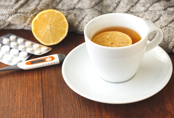 Pills for colds, thermometer and hot tea with lemon.