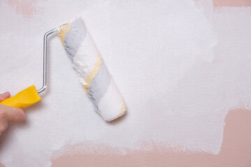 Obraz premium Painting the walls with a paint roller pink with white paint, home repairs.