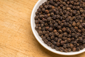 Black pepper in a white bowl on wooden Table