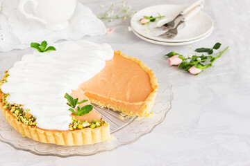 Grapefruit cream tart with pistachios and mint marble background.