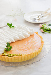 Grapefruit tart with whipped cream and pistachios on marble background.