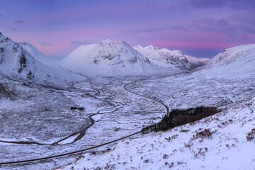 Long winding curvy road leading through impressive snow covered valley of Glencoe in the Scottish...