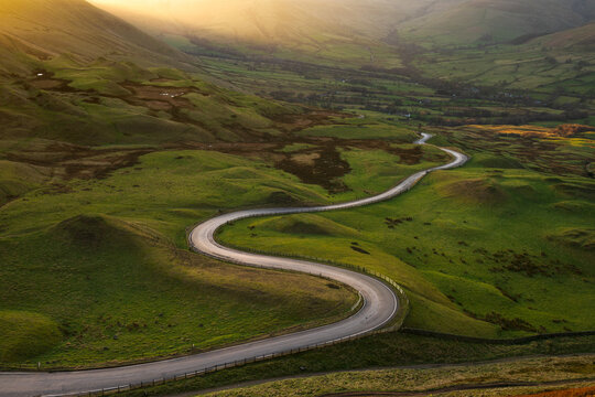 Long winding road in British rural countryside leading off into distance. Peak District, UK.