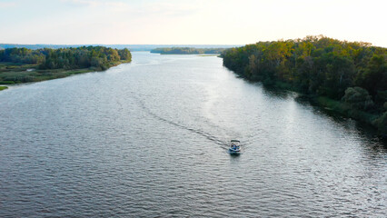 Photo from drone above a river with a slow drifting speedboat while sunset with people on board....