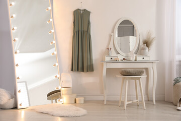 Large mirror with light bulbs and dressing table in stylish room. Interior design