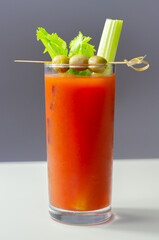 Bloody Mary cocktail prepared with pure vodka, tomato juice and hot pepper sauce, drink decorated with three olives and celery