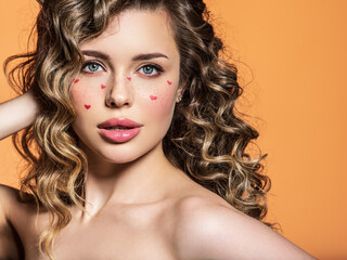 Portrait of a beautiful girl with painted red hearts on her face. Fashion photography. Sexy blonde...