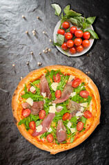 Italian pizza with ham and parmigiani chees on stone plate, and small sweet tomato with basil. basil, .