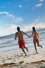 Couple running towards the ocean on the beach, Margarita Island, Venezuela