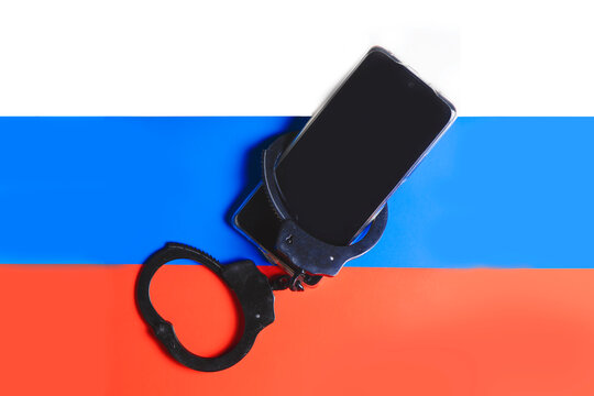 Freedom of the press in Russia. Handcuffs and smartphone on Russian flag background. - Powered by Adobe