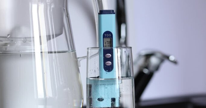 Filter for water purification. The mineralized water in the glass is checked using a tds meter. The concept of checking water quality with a special device. White background. Kitchen faucet 