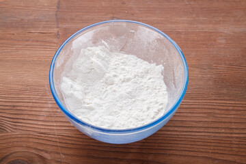 Confectionery flour in a bowl on a wooden table.