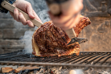 Closeup of a beautiful italian roasted steak on a barbeque grill. Appetizing piece of meat cooking on fire and embers in the backyard. Bbq, recreation, picnic, spring, summer, outdoors cook concept.