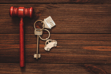 The key to the apartment with a keychain and car in the shape of a house on wooden background.