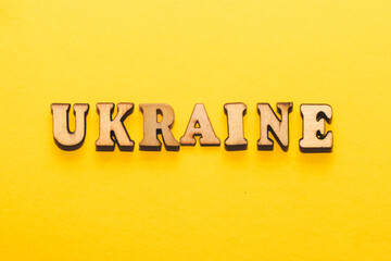 Wooden inscription Ukraine on a cardboard yellow background.
