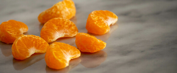 Close up of mandarin orange pieces on a marble surface.