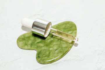 massage stone jade gouache scraper and facial roller with cosmetic cream.