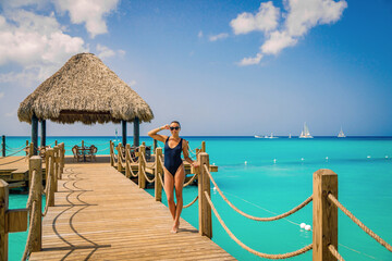 A young girl in a bathing suit stands on a wooden pier by the sea. Posing for the camera. High quality photo