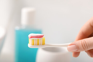 Fototapeta na wymiar Woman holding toothbrush with paste against blurred background, closeup