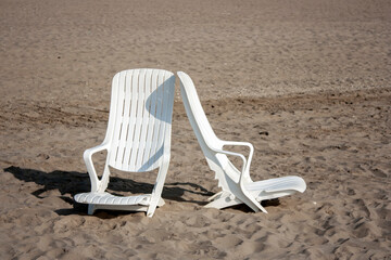Chairs on the sandy beach. Scenic view of two chairs on the beach. Two white beach chairs on a sandy beach.