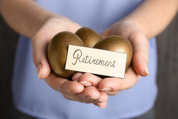 Woman holding golden eggs and card with word Retirement, closeup. Pension concept