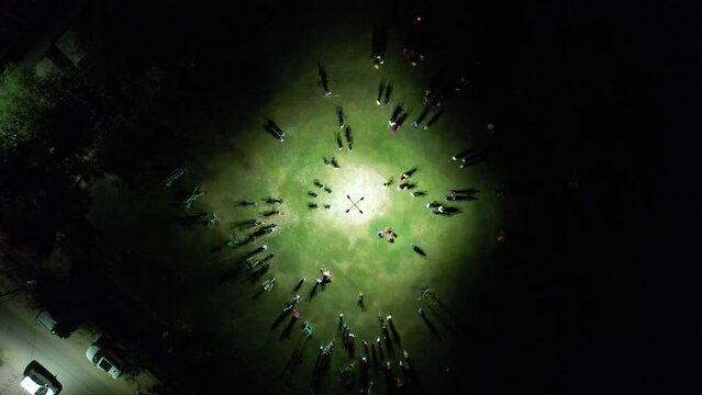aerial drone showing people moving around and about huge bonfire on green feild with lights on the hindu festival of holi lohri harvest