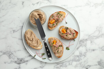 Slices of bread with delicious pate on white marble table, top view