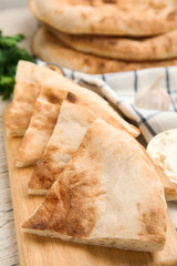 Cut pita bread on white wooden table, closeup