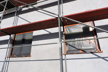 A scaffolding near a wall which is covered with prime before rendering exterior walls, windows and...