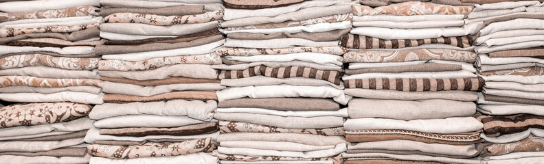 Stacks of linen fabric stacked. Factory for tailoring textiles. Warehouse clothes as a background.