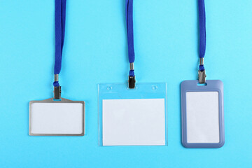 Blank badges on light blue background, flat lay. Mockup for design