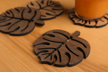 Many leaf shaped wooden cup coasters on table