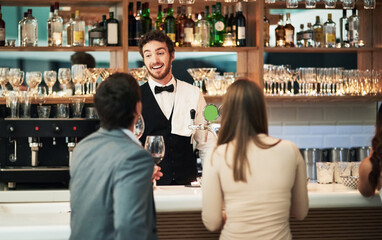 That sounds like a cocktail I can make. Cropped shot of a handsome young barman serving a young couple in a bar.
