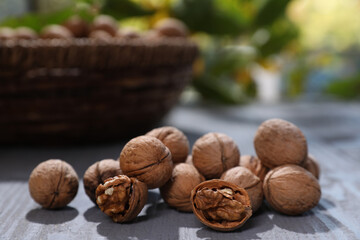 Pile of walnuts on grey wooden table outdoors. Space for text