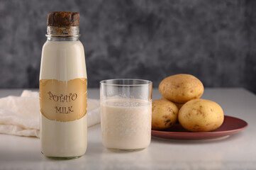 NO LOGO. NO POTATO MILK in a bottle and in a glass, Young potatoes on a plate