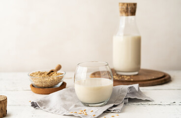 Oat milk in glass and bottle with raw seeds