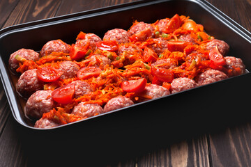 Raw meatballs with vegetables on a baking sheet are ready to bake in the oven. selective focus