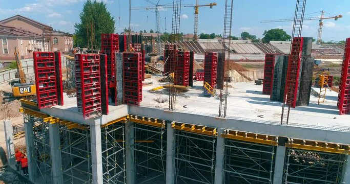 Builders make formwork at the construction site of a new stadium. Construction process of a modern football stadium. Aerial view of reinforced concrete construction