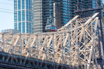 Fototapeta premium Roosevelt Island Tramway runs beside the Queensboro Bridge toward the high-rise residential building in Midtown Manhattan from Roosevelt Island on November 2021 New York City NY USA. 