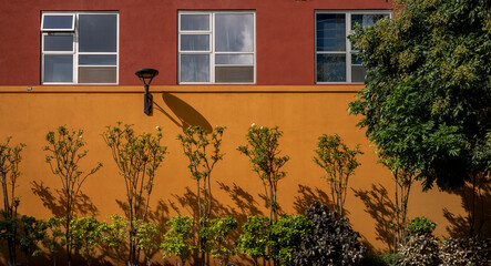 Red and Orange Building Wall With Green Plants.