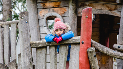 young girl playing in tree house in winter, sheltered by cold