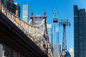 Roosevelt Island Tramway runs beside the Queensboro Bridge toward the high-rise residential building in Midtown Manhattan from Roosevelt Island on November 2021 New York City NY USA.
